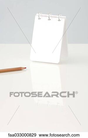 Stock Photo - Notepad upright on table, cropped view of pencil nearby. Fotosearch