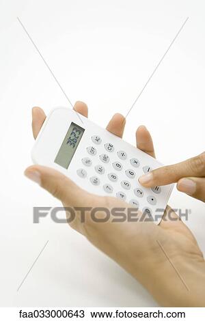 Stock Image - Person using calculator, cropped view of hands. Fotosearch