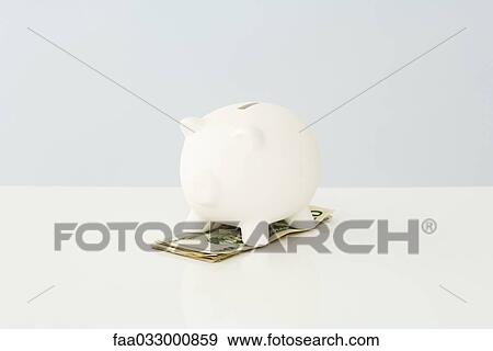 Stock Photo - Piggy bank on top of a small pile of twenty dollar bills. Fotosearch