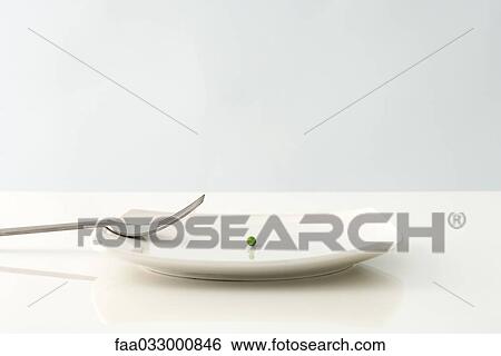 Stock Photograph - Single pea on a plate, fork resting off to the side. Fotosearch