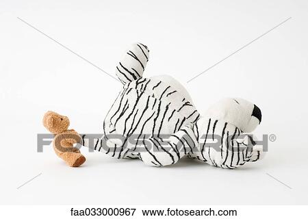 Stock Photo - Small teddy bear pulling large stuffed tiger's tail. Fotosearch