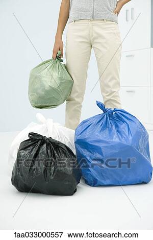 Stock Photo - Teen girl with several bags of garbage, cropped view. Fotosearch