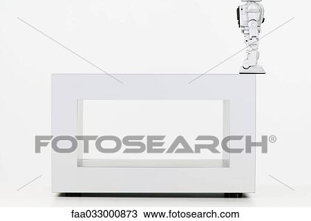 Toy robot perched at the edge of coffee table, cropped side view View Large Photo Image Stock Image - Toy robot perched at the edge of coffee table, cropped side view. Fotosearch