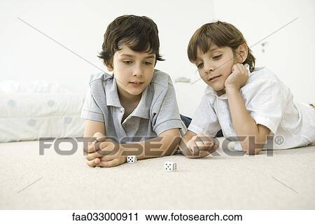 Two boys lying on the floor looking down at a pair of dice View Large Photo Image Stock Image - Two boys lying on the floor looking down at a pair of dice. Fotosearch