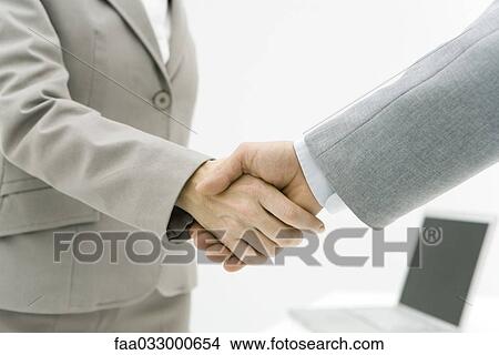 Picture - Two business associates shaking hands, cropped view. Fotosearch