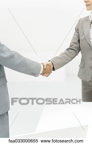 Two business associates shaking hands, cropped view View Large Photo Image Stock Photography - Two business associates shaking hands, cropped view. Fotosearch
