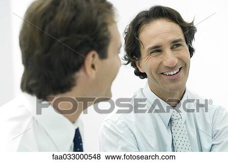 Two colleagues smiling, focus on man in background View Large Photo Image Stock Photo - Two colleagues smiling, focus on man in background. Fotosearch