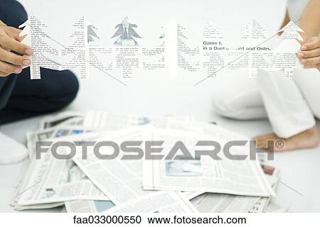 Stock Image - Two people holding tree shapes cut out of newspaper, cropped view. Fotosearch