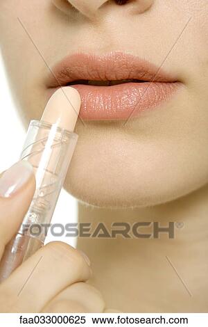 Stock Photography - Woman applying lipstick, extreme close-up. Fotosearch