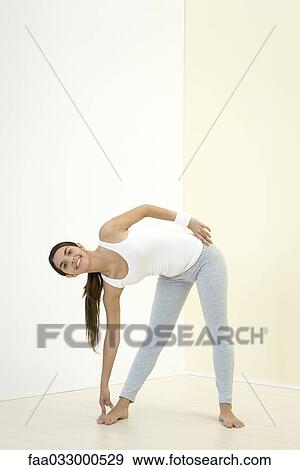 Woman bending over to touch her toes, smiling at camera View Large Photo Image Stock Photo - Woman bending over to touch her toes, smiling at camera. Fotosearch