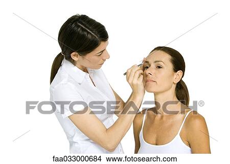 Picture - Woman having eyebrows tweezed, frowning. Fotosearch