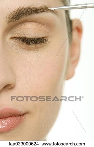 Picture - Woman having make-up applied to eyebrow, eyes closed, cropped. Fotosearch