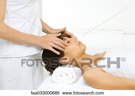 Stock Photography - Woman lying down, receiving head massage, side view. Fotosearch