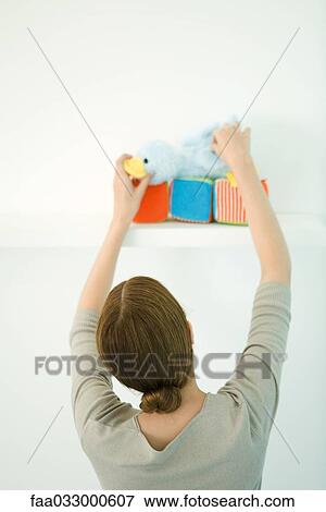 Woman placing stuffed toy on shelf, rear view View Large Photo Image Stock Photo - Woman placing stuffed toy on shelf, rear view. Fotosearch