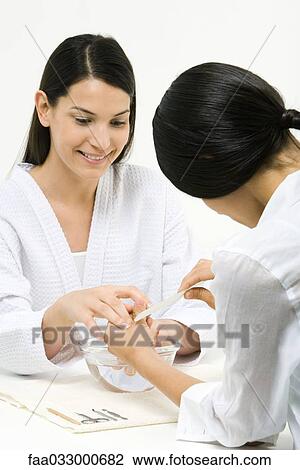 Stock Image - Woman receiving manicure, smiling. Fotosearch