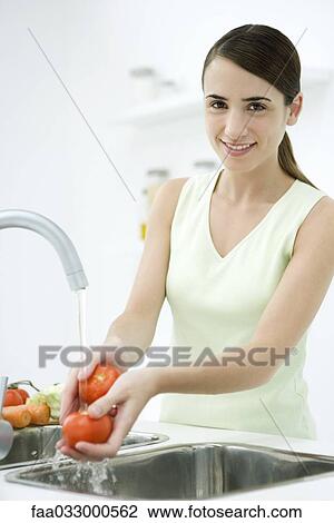 Woman rincing tomatoes in kitchen sink, smiling at camera View Large Photo Image Stock Image - Woman rincing tomatoes in kitchen sink, smiling at camera. Fotosearch