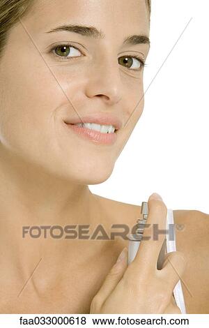 Woman spraying perfume on her neck, smiling at camera View Large Photo Image Stock Photo - Woman spraying perfume on her neck, smiling at camera. Fotosearch