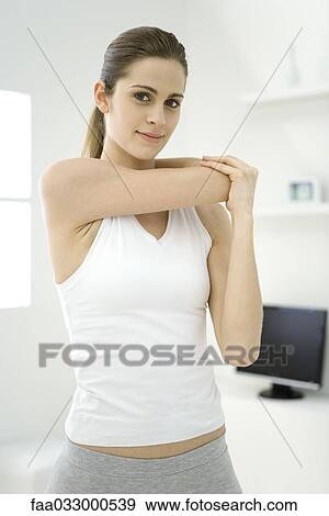 Woman stretching her arm, smiling at camera View Large Photo Image Stock Photo - Woman stretching her arm, smiling at camera. Fotosearch