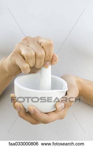 Stock Photograph - Woman using mortar and pestle, close-up, cropped view. Fotosearch