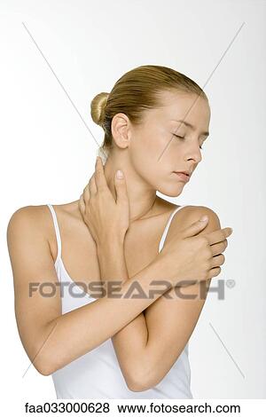 Stock Photo - Woman with arms folded across chest, touching neck, eyes closed. Fotosearch