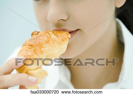 Young woman eating croissant, close-up, cropped view View Large Photo Image Stock Image - Young woman eating croissant, close-up, cropped view. Fotosearch