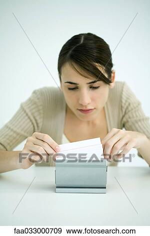 Stock Photo - Young woman looking through box of index cards. Fotosearch