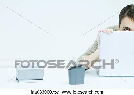 Young woman peeking over laptop, cropped view View Large Photo Image Stock Photo - Young woman peeking over laptop, cropped view. Fotosearch