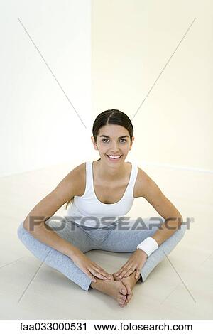 Young woman sitting on the ground, stretching, smiling at camera View Large Photo Image Stock Image - Young woman sitting on the ground, stretching, smiling at camera. Fotosearch