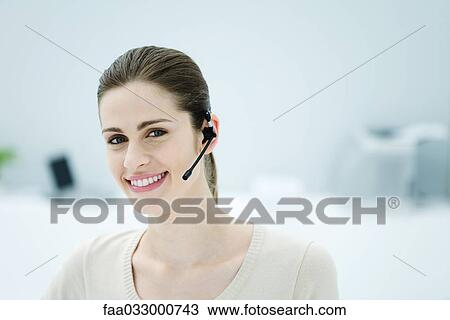 Young woman wearing headset, smiling at camera, portrait View Large Photo Image Stock Image - Young woman wearing headset, smiling at camera, portrait. Fotosearch