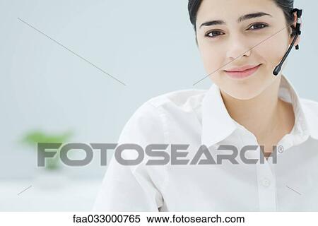 Stock Photography - Young woman wearing headset, smiling at camera, portrait. Fotosearch