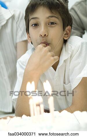 Boy in front of birthday cake with lit candles, tasting frosting with finger View Large Photo Image Stock Image - Boy in front of birthday cake with lit candles, tasting frosting with finger. Fotosearch