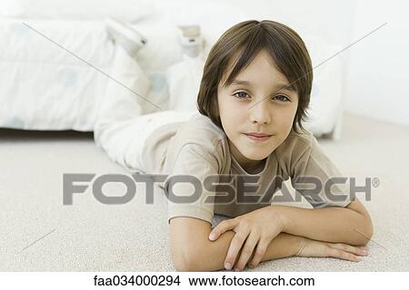 Boy lying on the floor in bedroom, smiling at camera View Large Photo Image Picture - Boy lying on the floor in bedroom, smiling at camera. Fotosearch