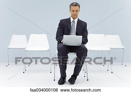 Business man sitting alone in room using laptop computer View Large Photo Image Stock Photo - Business man sitting alone in room using laptop computer. Fotosearch