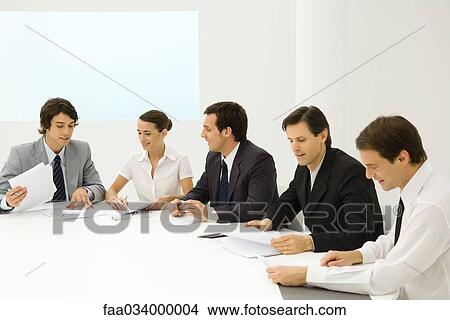 Business people in meeting, reviewing documents View Large Photo Image Picture - Business people in meeting, reviewing documents. Fotosearch