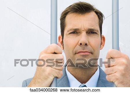 Businessman behind bars, frowning at camera View Large Photo Image Stock Photo - Businessman behind bars, frowning at camera. Fotosearch