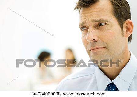 Stock Photo - Businessman furrowing brow, looking out of frame, close-up. Fotosearch