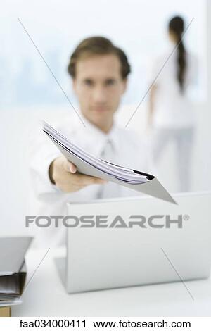 Businessman holding folder toward camera, focus on foreground View Large Photo Image Stock Image - Businessman holding folder toward camera, focus on foreground. Fotosearch
