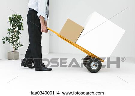 Businessman moving boxes with hand truck View Large Photo Image Picture - Businessman moving boxes with hand truck. Fotosearch