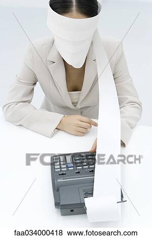 Stock Photo - Businesswoman using adding machine, blindfolded with paper printout. Fotosearch