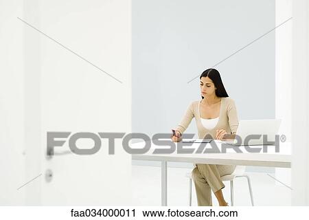 Stock Image - Businesswoman working alone in empty office. Fotosearch