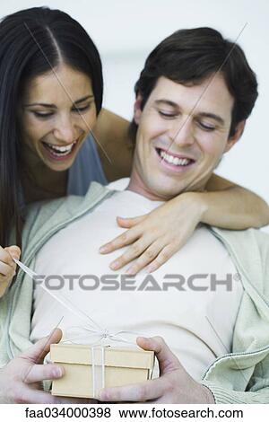 Couple opening gift together, laughing View Large Photo Image Stock Photo - Couple opening gift together, laughing. Fotosearch