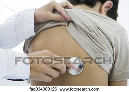 Stock Photograph - Doctor holding stethoscope against boy's back, cropped view. Fotosearch