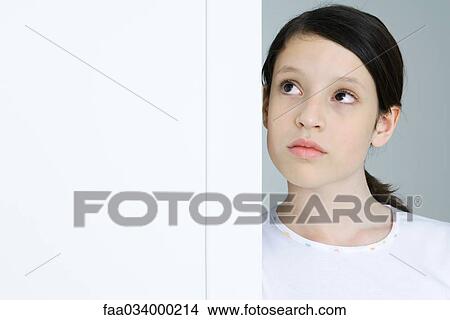 Picture - Girl leaning against doorway, looking up, portrait. Fotosearch