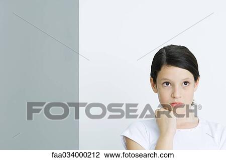 Stock Image - Girl looking up, hand under chin. Fotosearch