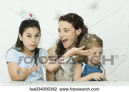 Stock Image - Girl throwing confetti, mother and sister watching. Fotosearch