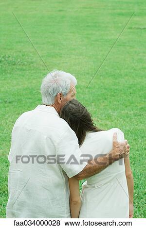 Stock Photo - Grandfather with teenage granddaughter, arm around her shoulder, her head on his shoulder. Fotosearch