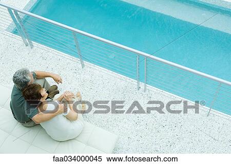 Husband and wife sitting by pool, his arm around her shoulder, her head on his View Large Photo Image Stock Photography - Husband and wife sitting by pool, his arm around her shoulder, her head on his. Fotosearch
