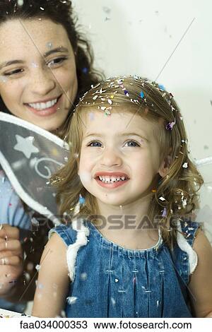 Little girl watching confetti fall, mother behind her, both smiling View Large Photo Image Stock Image - Little girl watching confetti fall, mother behind her, both smiling. Fotosearch
