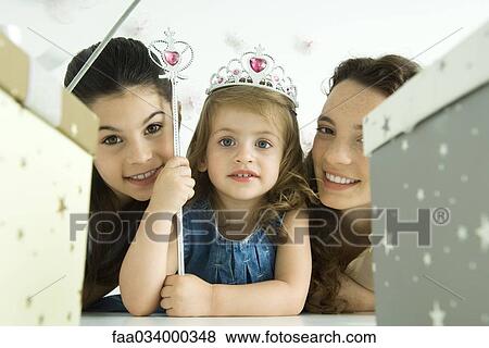 Stock Photo - Little girl with mother and sister, dressed as princess, birthday gifts in foreground. Fotosearch
