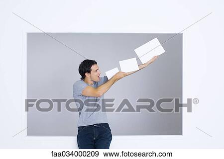 Stock Photo - Man holding up blank papers, shouting. Fotosearch